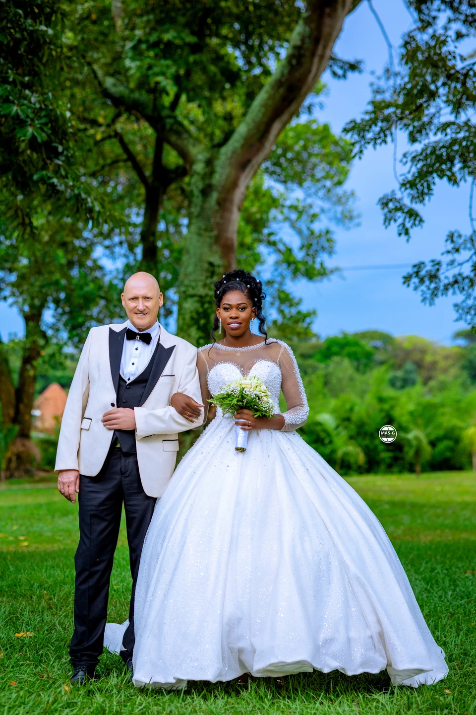Bride and groom standing together beneath garden trees